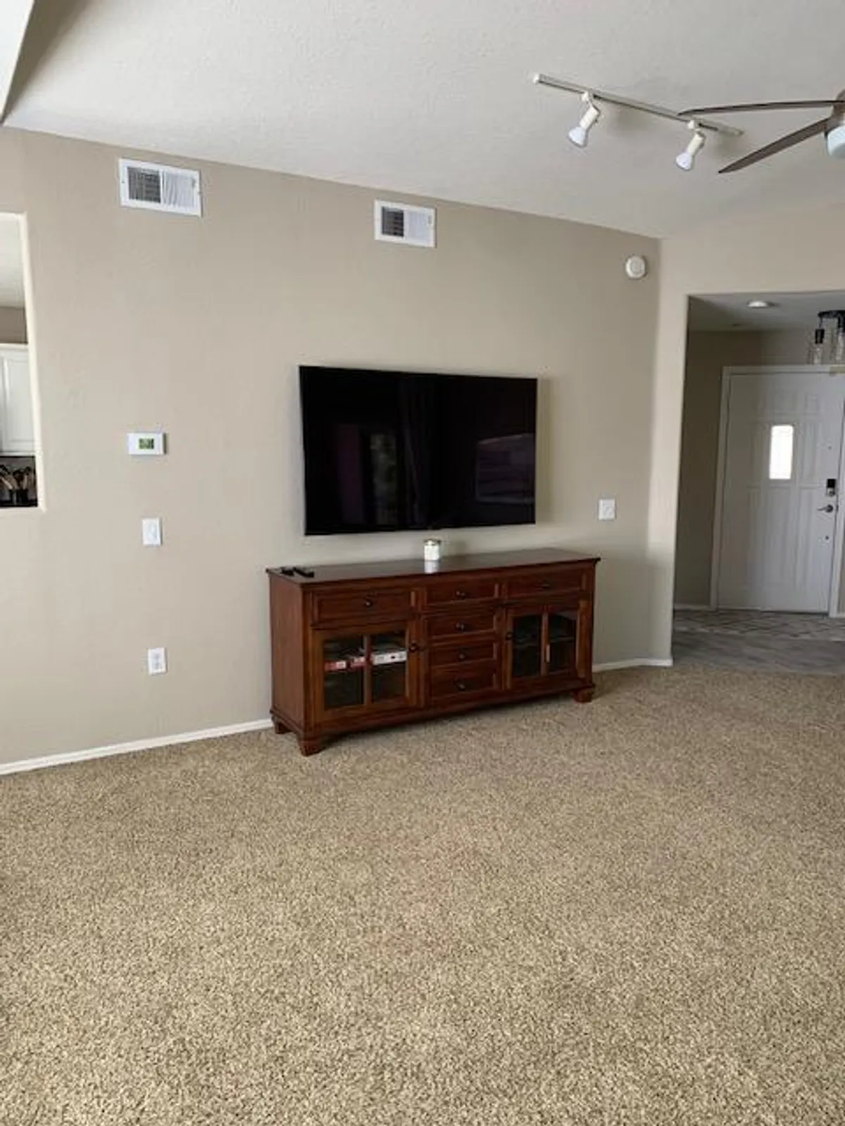 A cozy room showcasing a television atop a wooden cabinet, with inviting lighting and a comfortable atmosphere. The space suggests an area where guests might enjoy meals or snacks while watching TV, making it adjacent to or part of the dining/kitchen zone in a modern home.