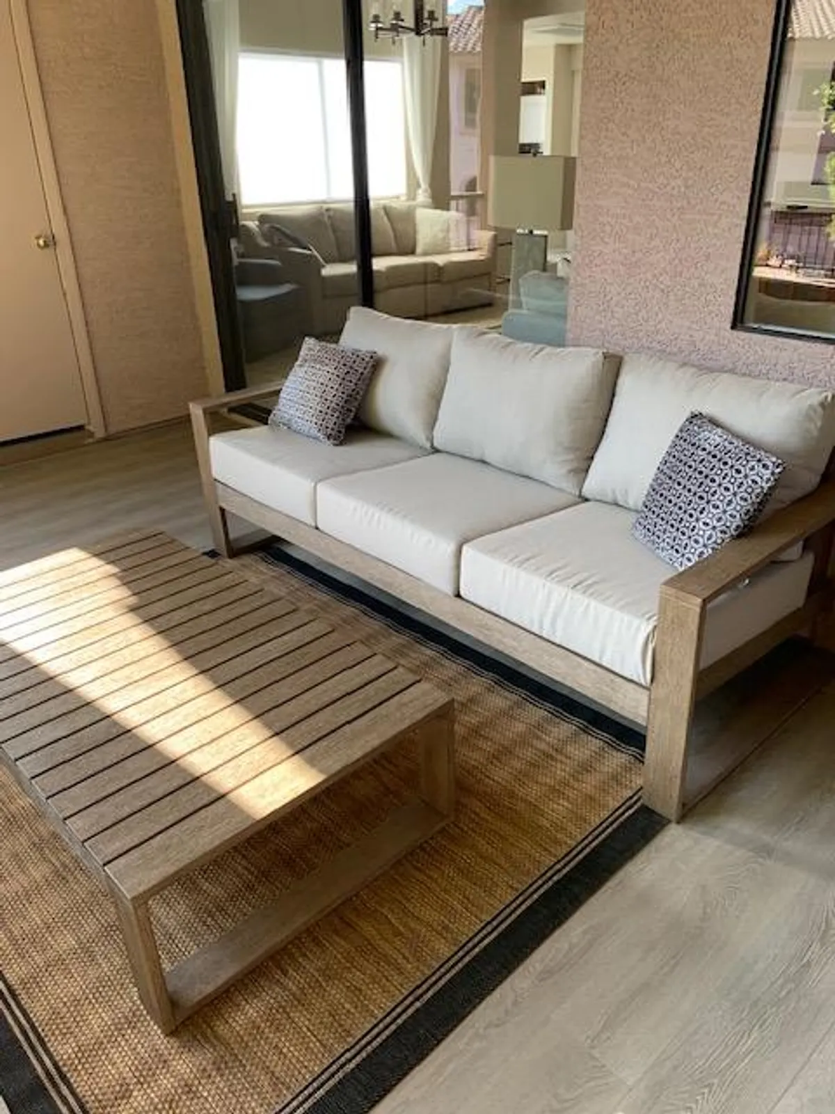 A bright, inviting living space with a light-colored sofa, wooden coffee table, decorative pillows, and a woven rug. Natural light streams in, creating a perfect setting for morning coffee or casual dining experiences. The decor suggests a seamless blend of comfort and style.