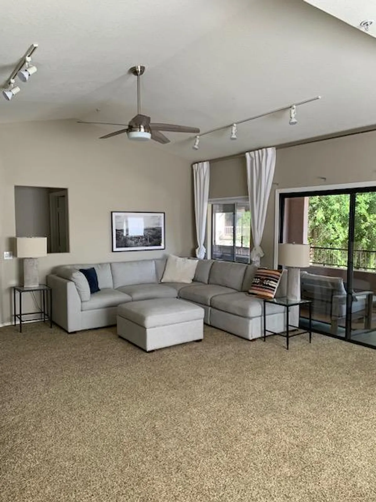 A cozy living space featuring a plush sofa arranged near warm lighting from lamps, large window letting in natural light, and tasteful artwork on the wall. The scene suggests a welcoming place for families to relax, socialize, or unwind after a day of adventures.