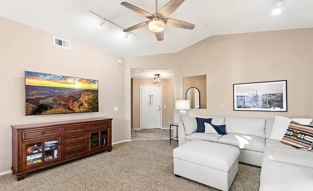 A cozy living area spotlighting a large TV displaying a scenic landscape, a plush sectional couch, and a sleek wooden media console. The setup encourages movie nights, gaming, or simply relaxing after a busy day.