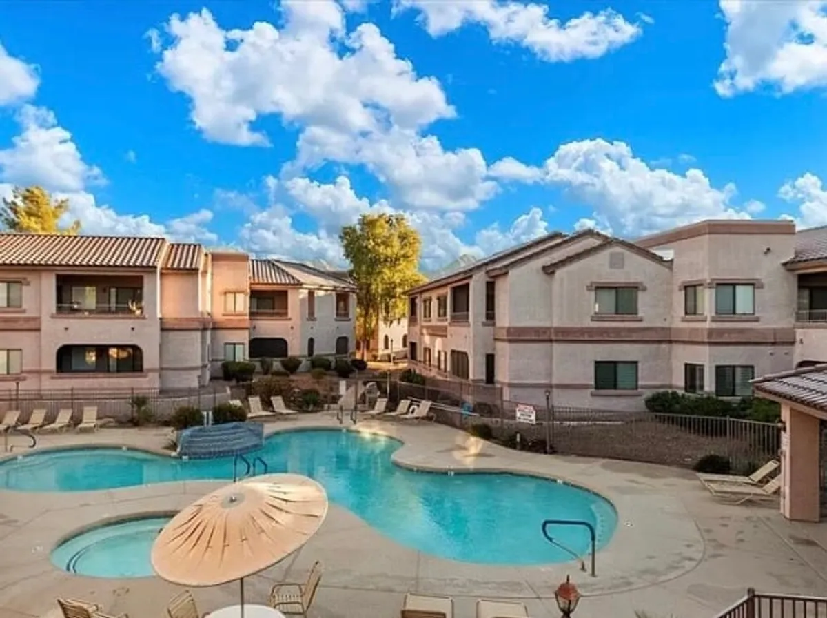 A vibrant scene of the sparkling swimming pool surrounded by building exteriors, lounge chairs, and umbrellas, with a lively mood that suggests community and fun. The image hints at various activities, from swimming to social gatherings.