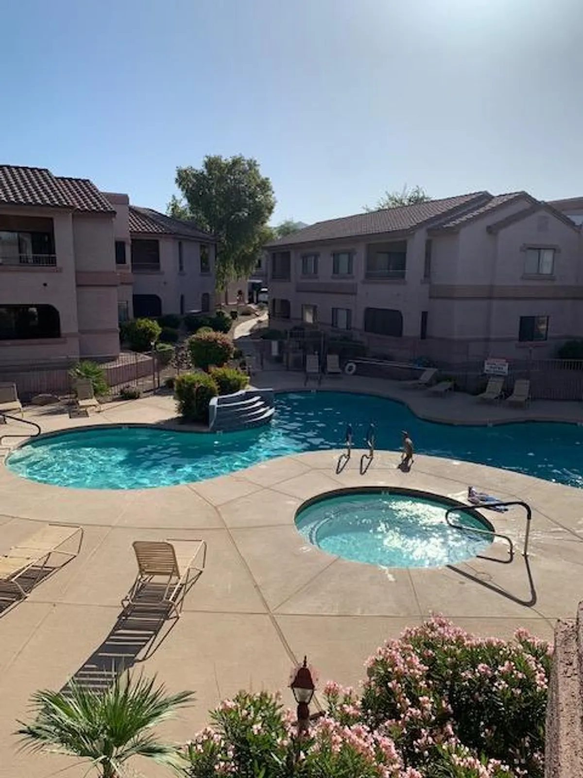 This scene highlights a pool area with a hot tub, abundant greenery, and a comfortable seating spot—blending relaxation and a natural environment. The tranquil mood invites residents to enjoy a quiet soak or a casual chat by the water.
